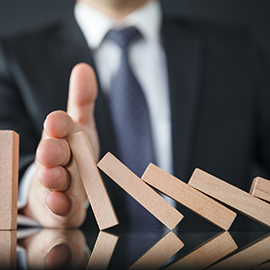 A hand preventing the domino effect of blocks falling over