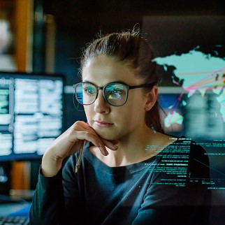 A woman looking thoughtful in front of multiple computer screens