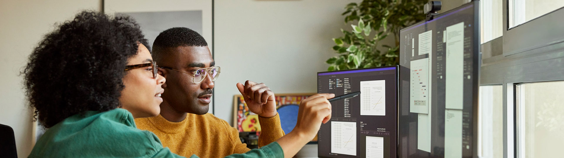 A man and a woman discussing data on a computer screen