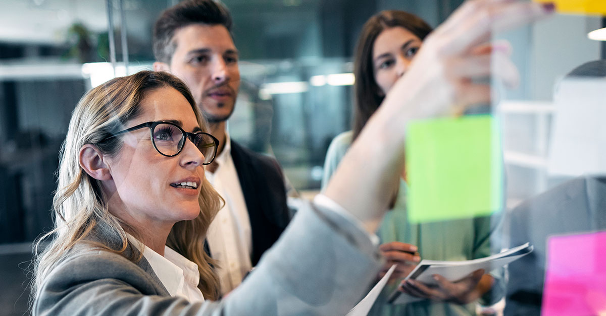 A woman sticking post-it notes on a transparent wall