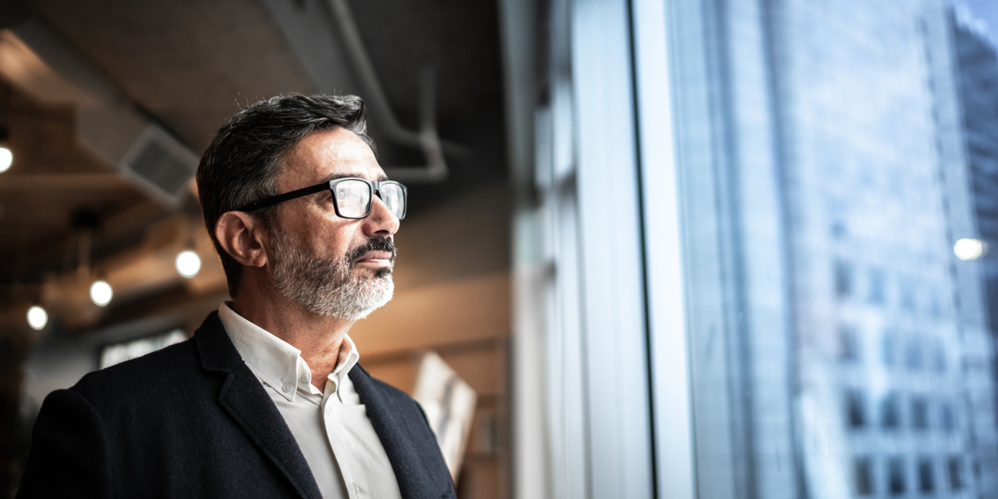 Business man wearing glasses looking out of window