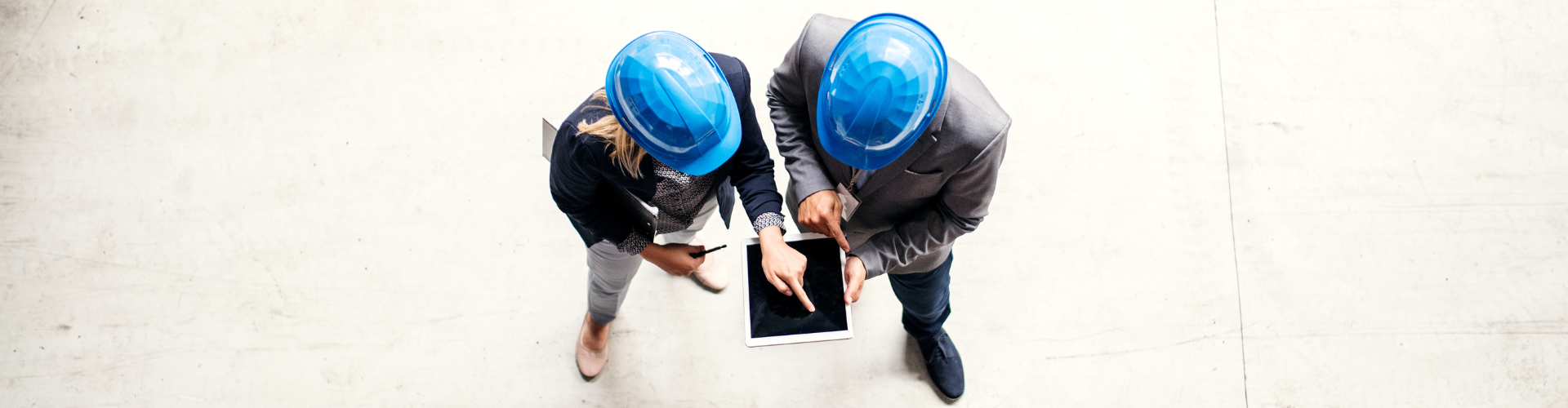 2 people in hard hats holding tablet