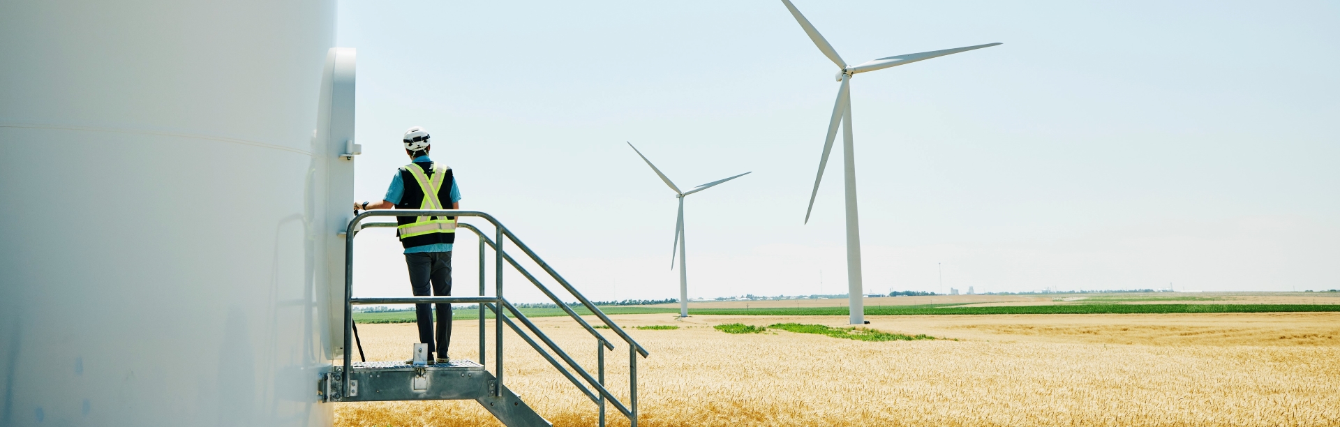 A man in a hard hat about to enter a wind turbine