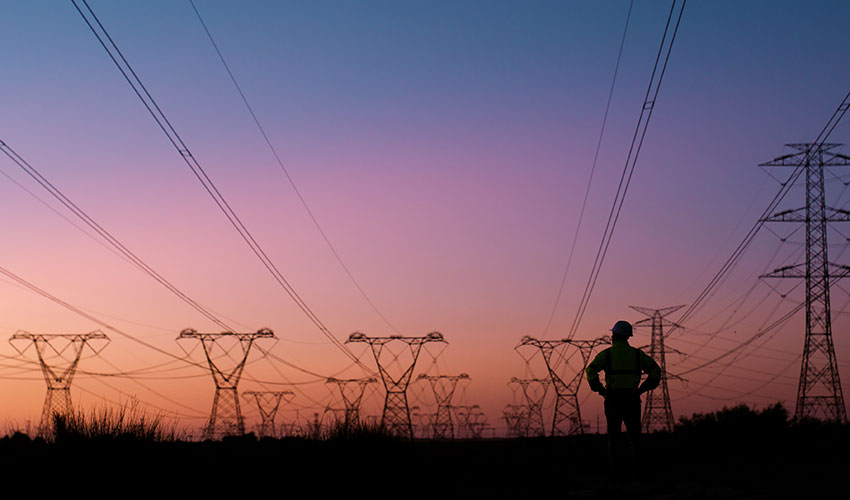 Engineer looking at power lines at dusk