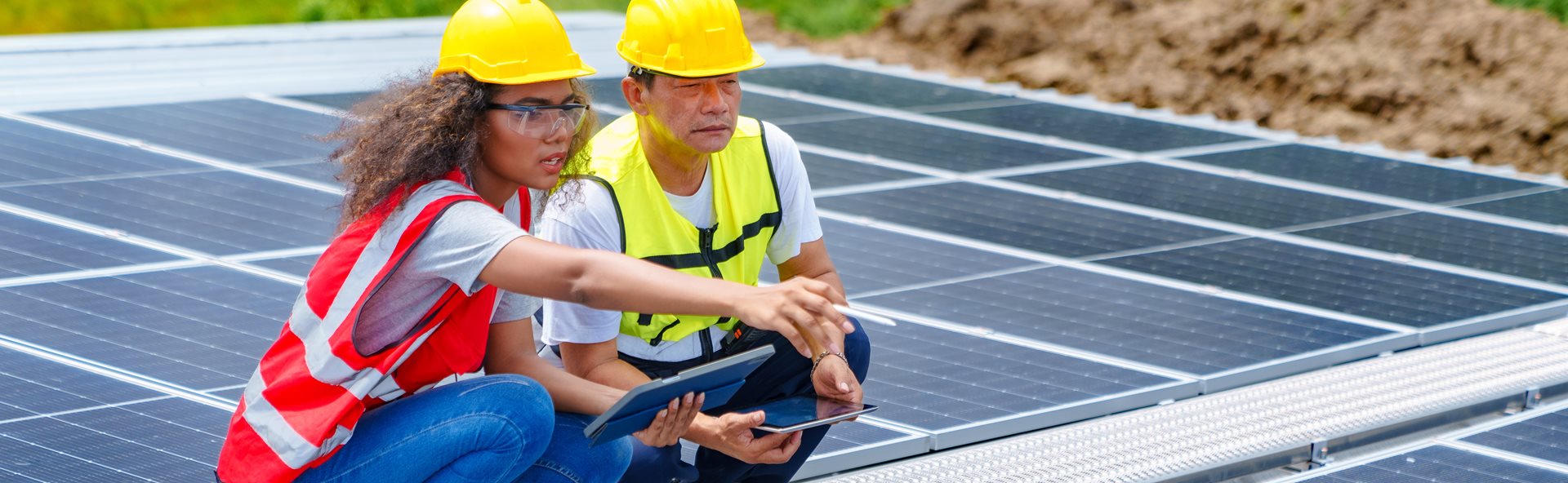 Two engineers analysing data while working with solar panels on a roof