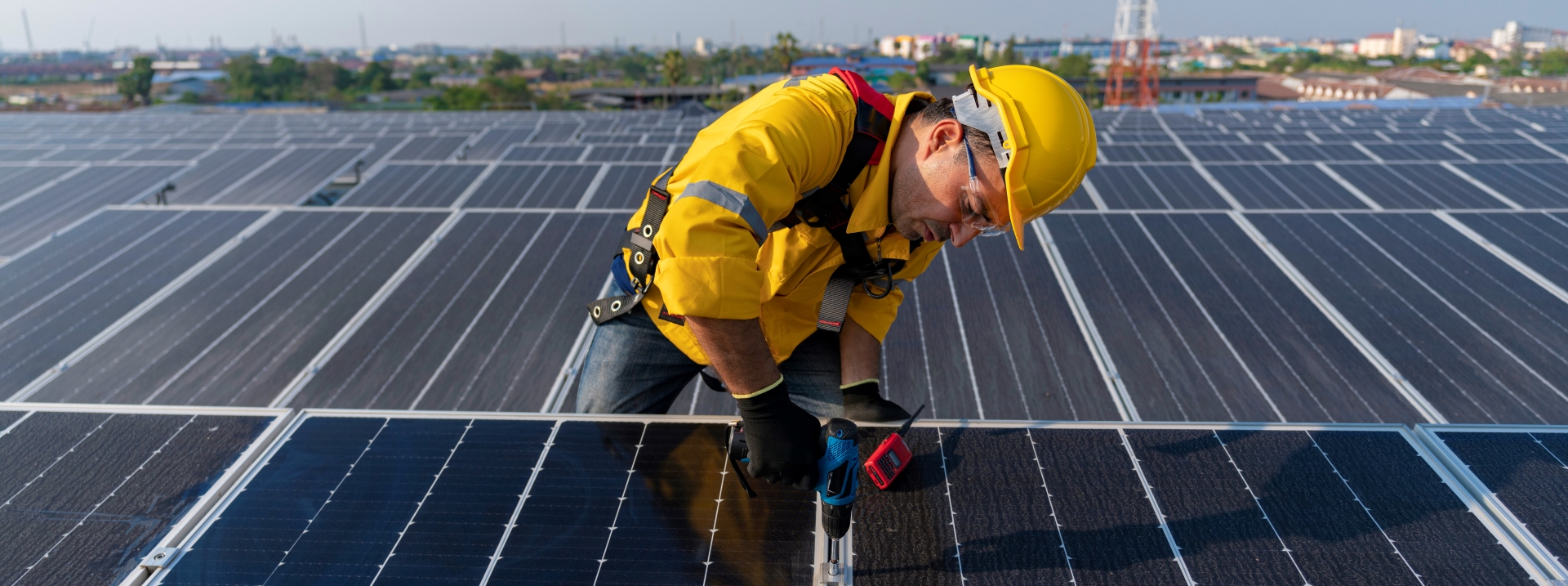 A man in hard hat working on panels at a solar farm