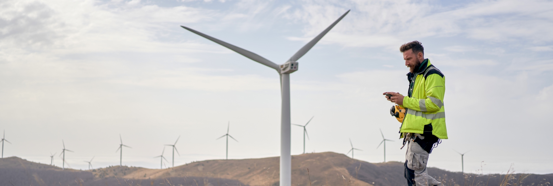A man looking at his phone at a windfarm