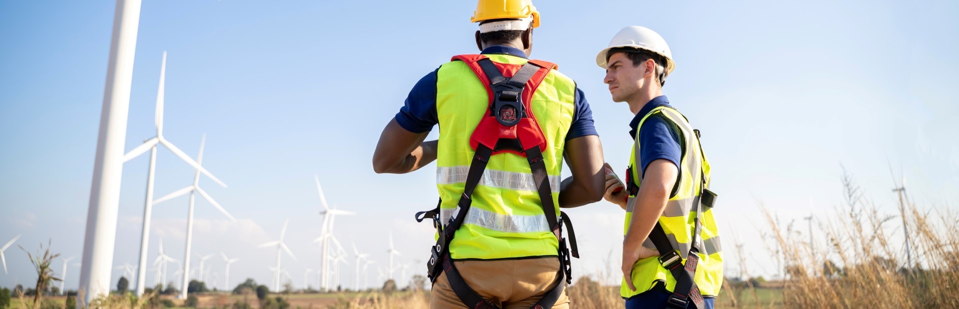 Two maintenance men wearing harnesses at a windfarm