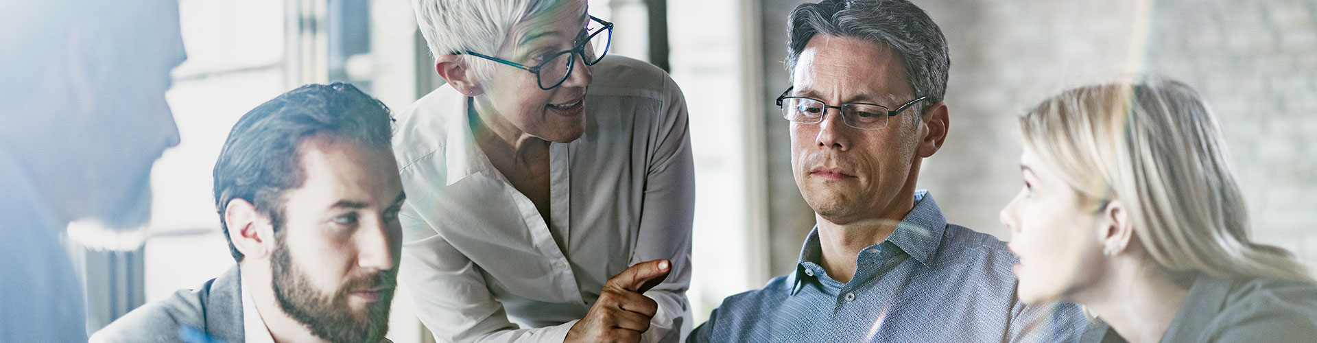 Team of business colleagues talking while working on computer in the office