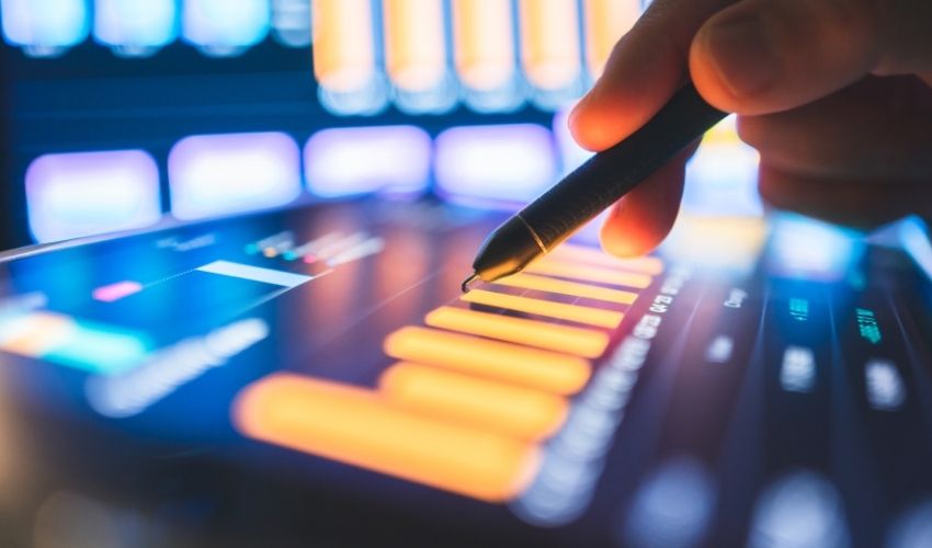 Close-up of a hand using a stylus on a digital tablet displaying financial data charts