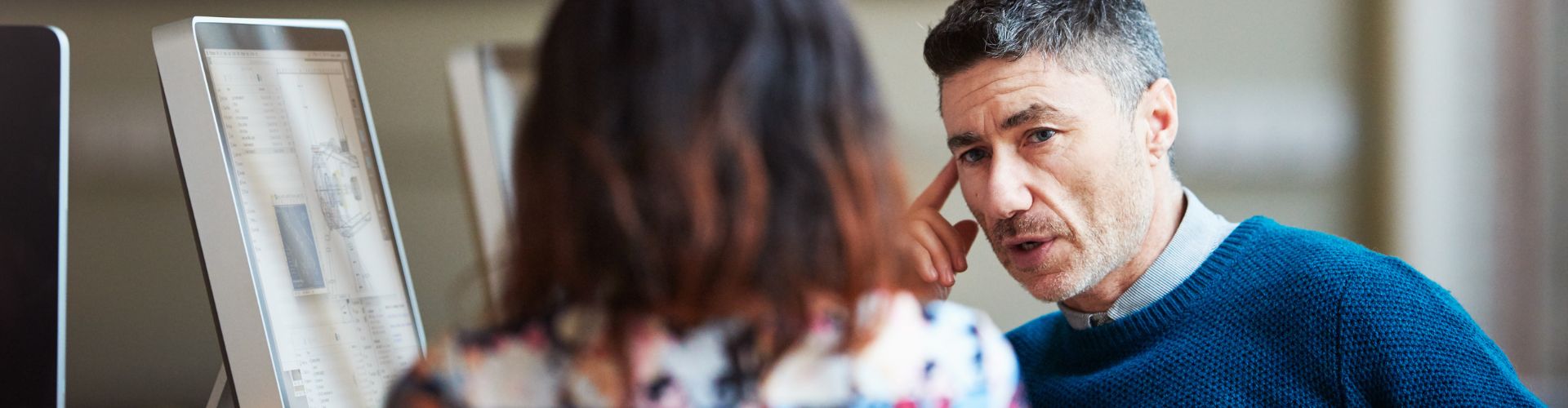 Man and woman talking in front of computers 
