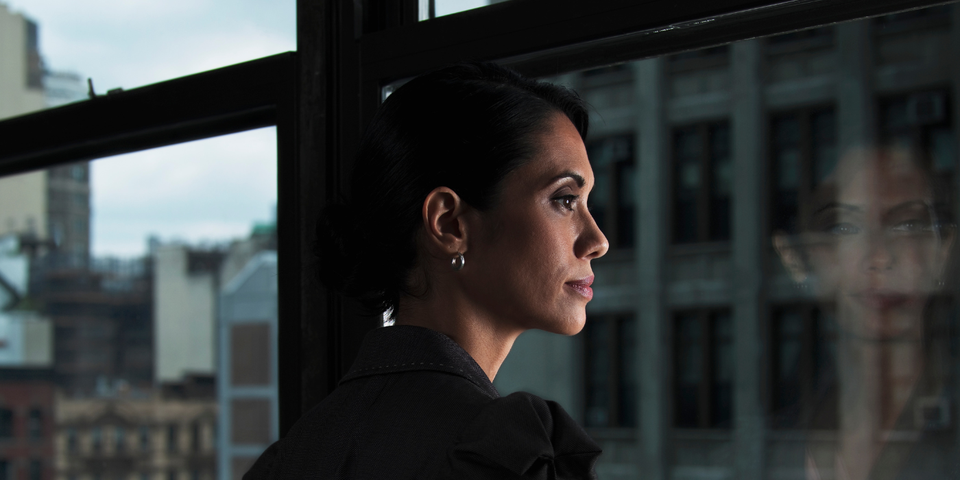 Woman looking over city, reflected in window