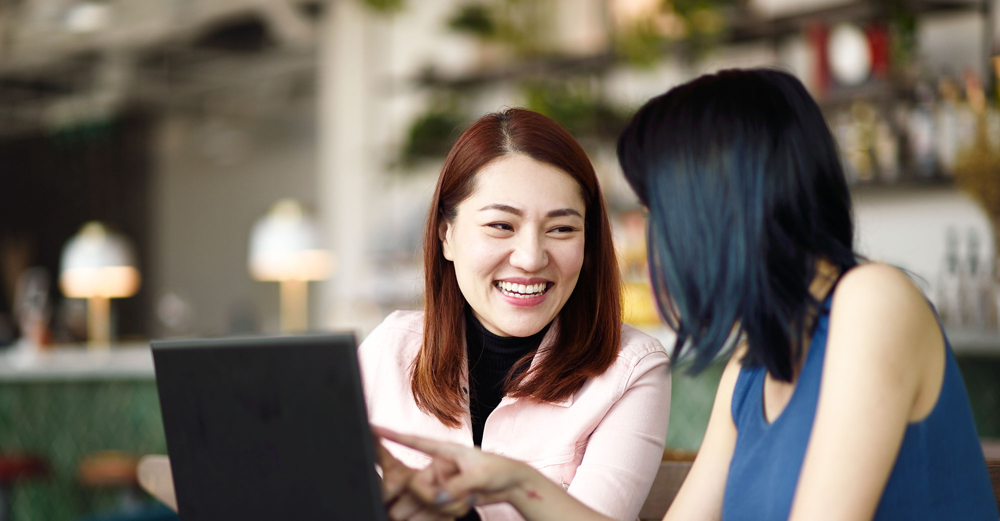 Two women talking in front of a laptop