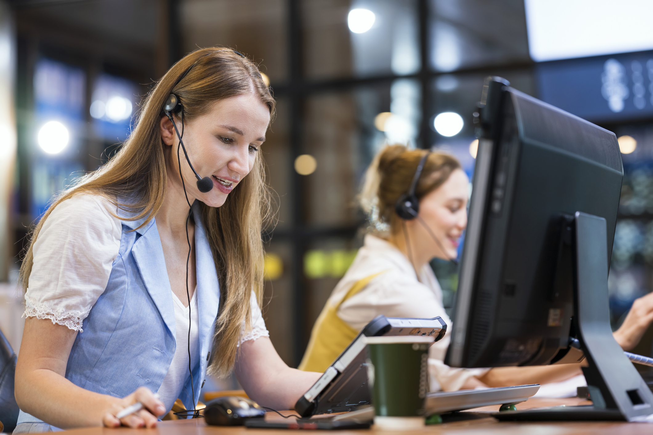 A woman wearing a headset in front of a computer