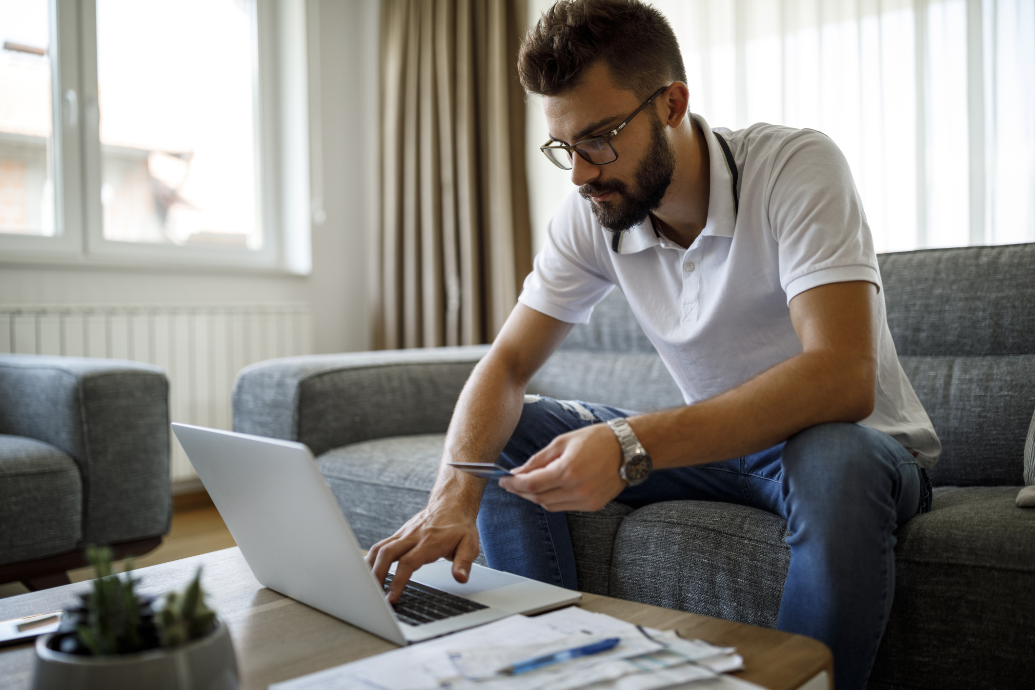 Man sitting on a sofa and making a payment on his laptop