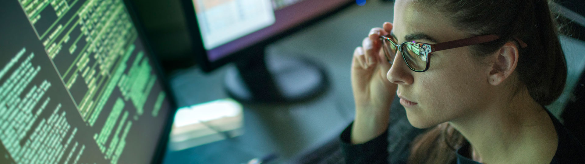 A woman with glasses looking at a computer screen