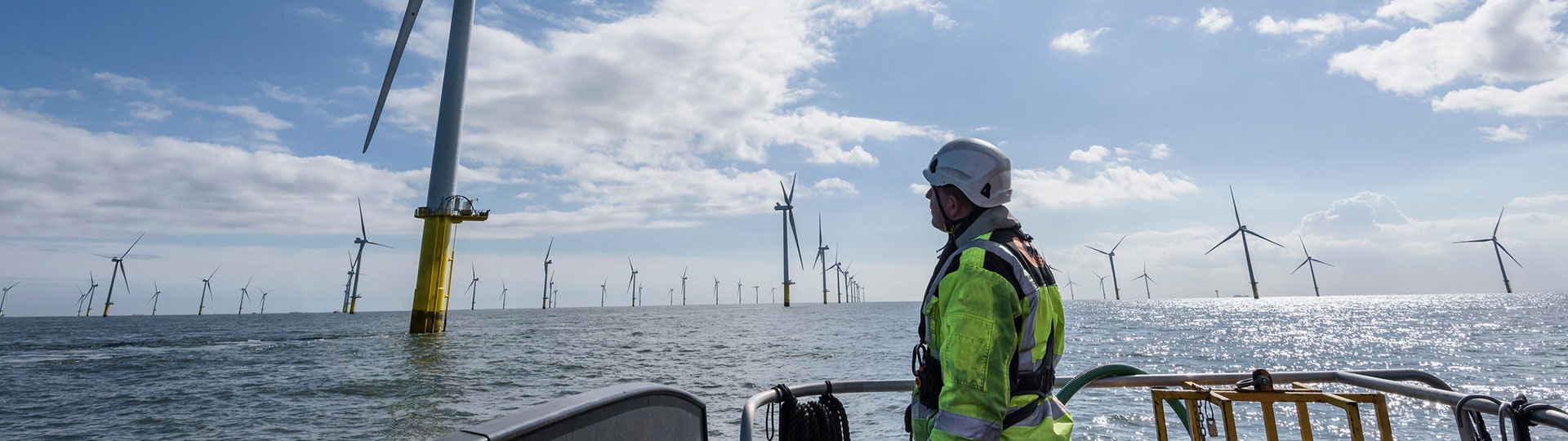 An engineer in a boat approaching an offshore wind farm