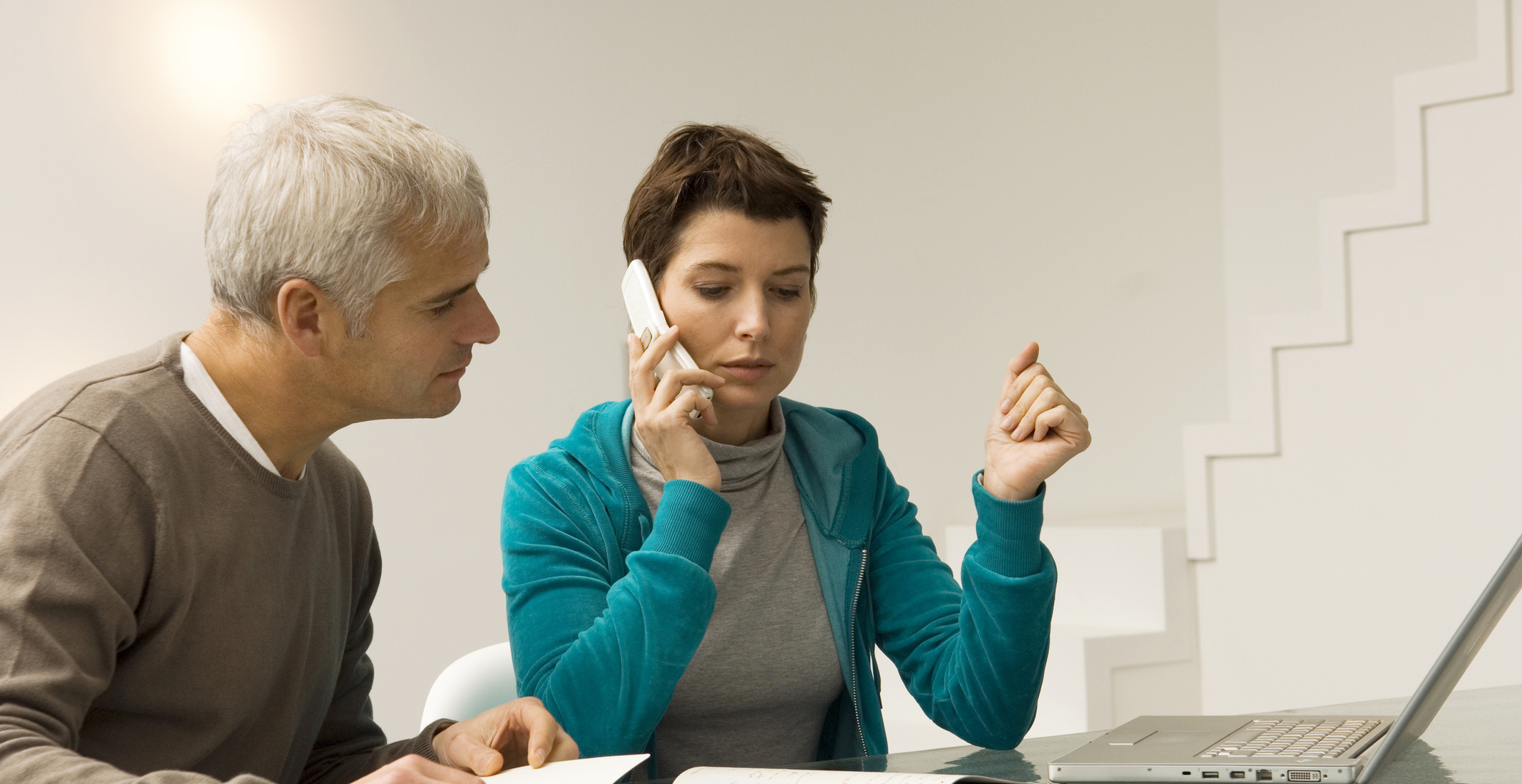 Two people looking at bills and calling on the phone