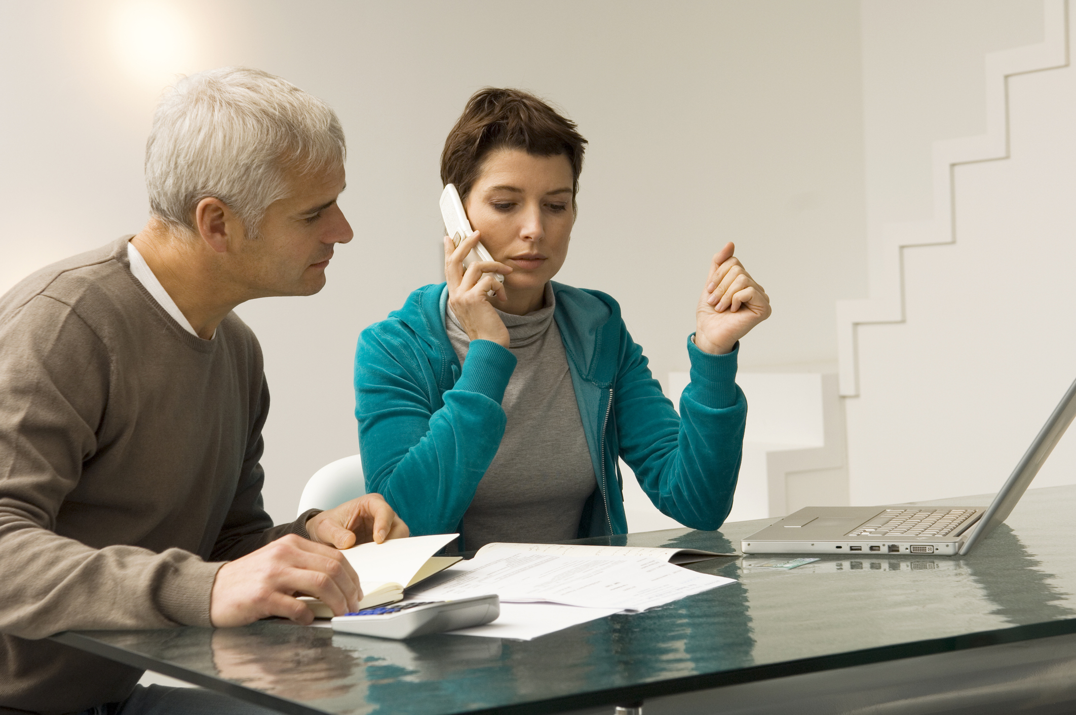 Two people looking at bills and calling on the phone