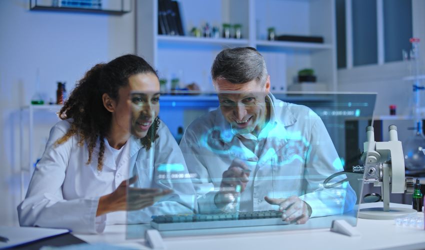Two people in lab coats looking at a monitor