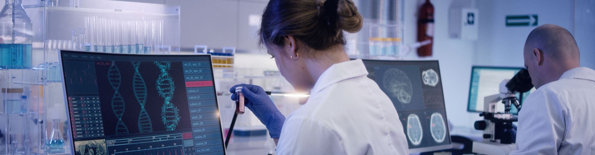 Scientists working in a high-tech laboratory with DNA data on computer screens