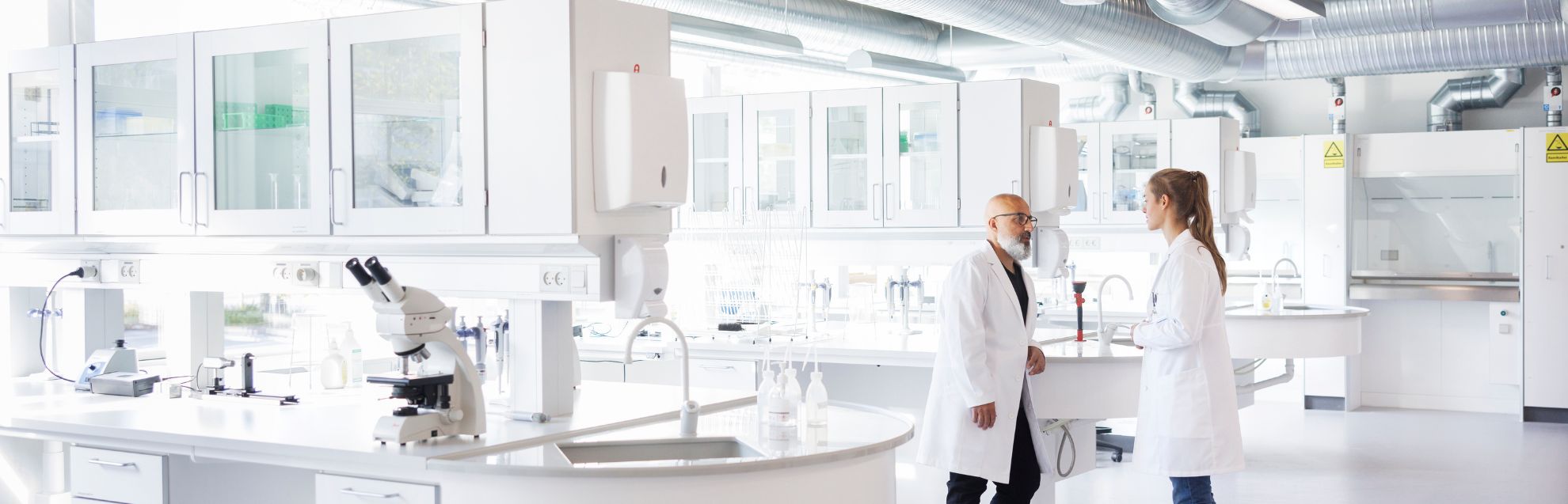 Two scientists in conversation, standing in laboratory