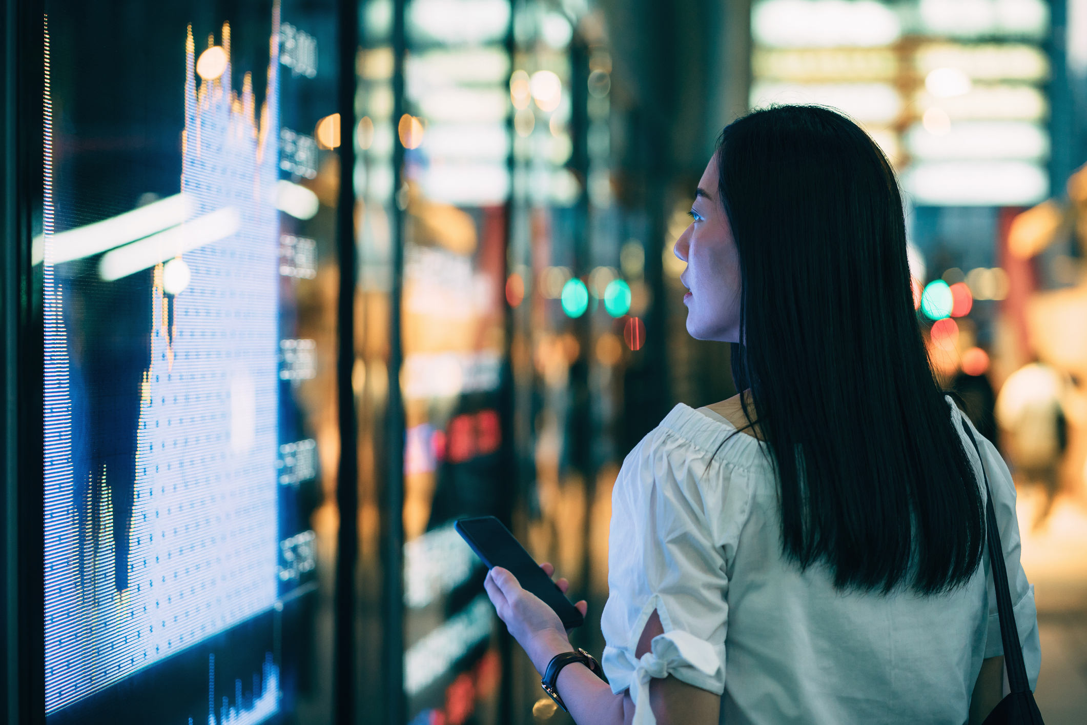 A woman holding her phone while looking at data on her phone