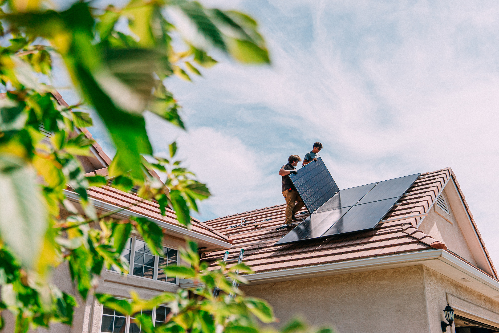 men installing solar panels on the roof of a home