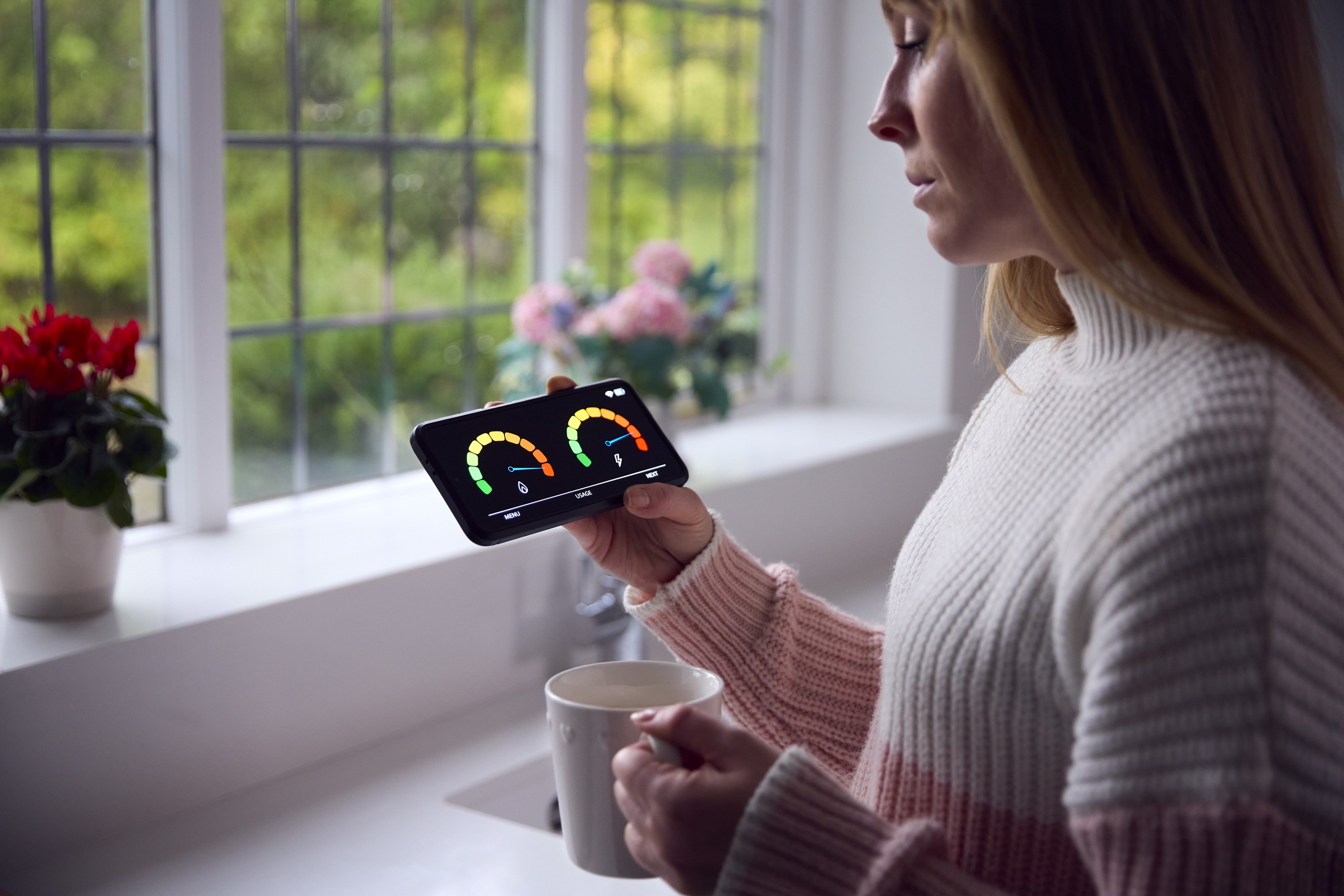 A woman standing in her home looking at a smart meter