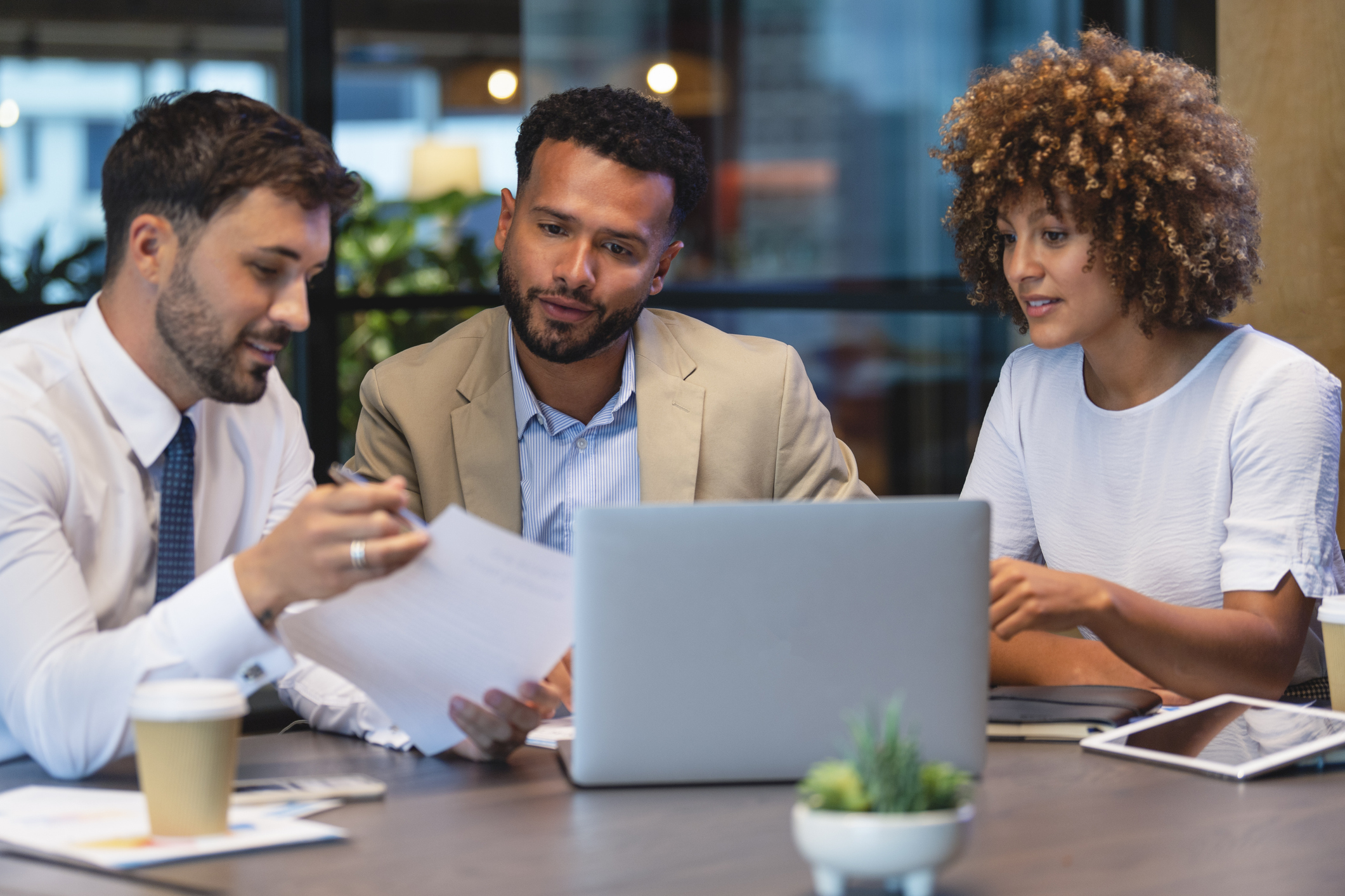 Three colleagues discussing plans in front of a laptop