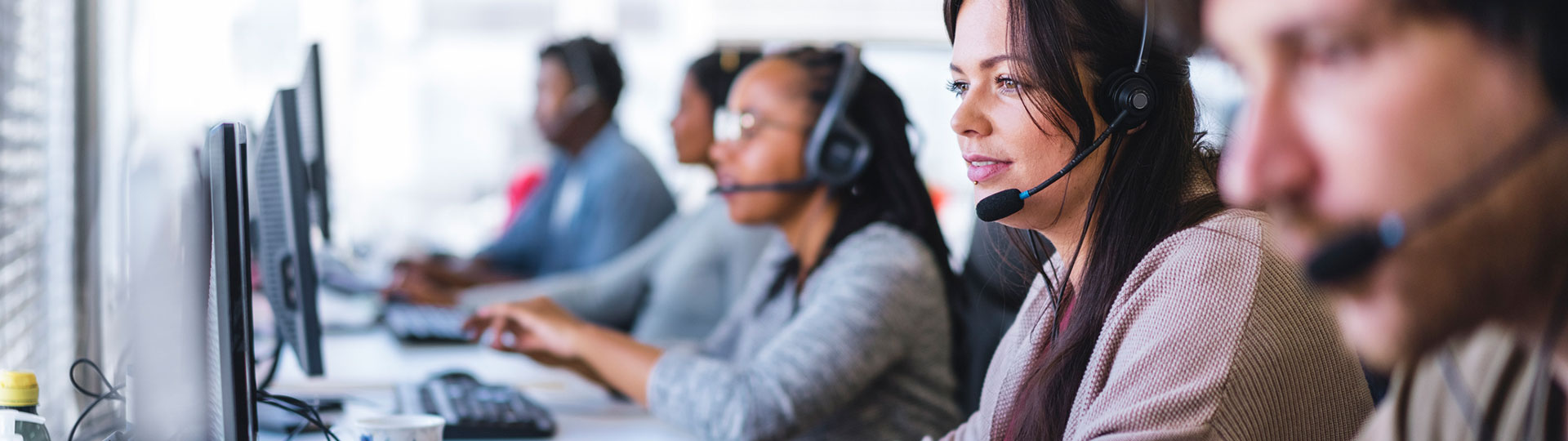 Call centre staff wearing headsets in front of their computers