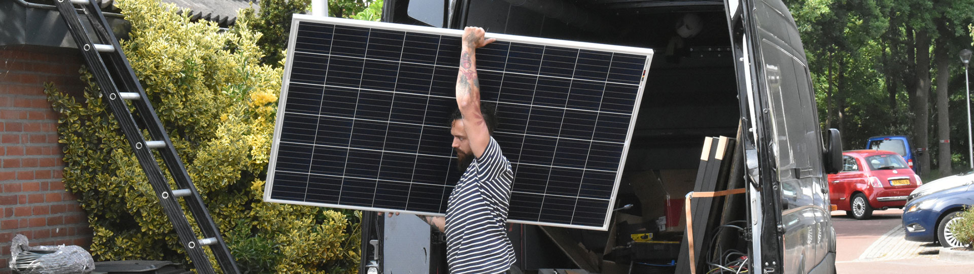 A man taking a solar panel out of a van