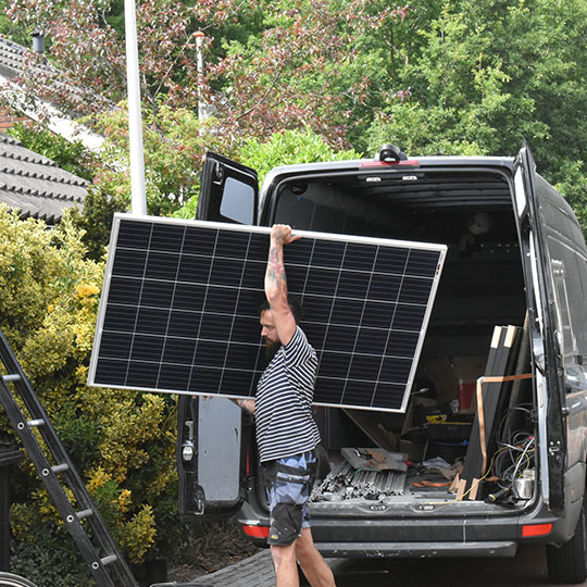 A man taking a solar panel out of a van