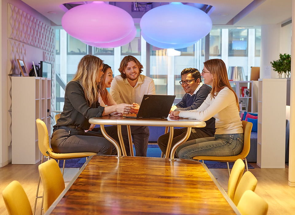 Office discussion around a round table with five colleagues