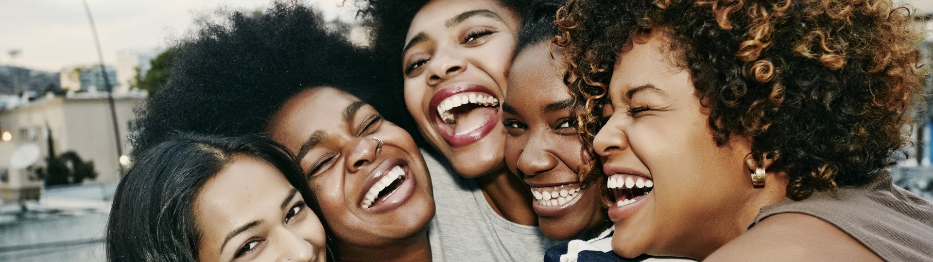 A group of black girlfriends hug and laugh