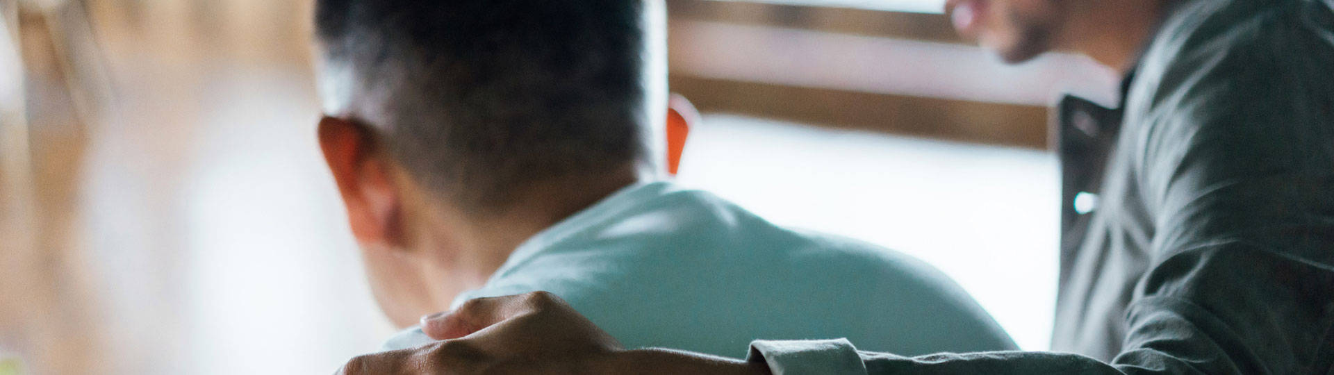 A man standing with his arm around someone comforting them