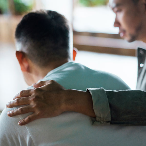 A man standing with his arm around someone comforting them