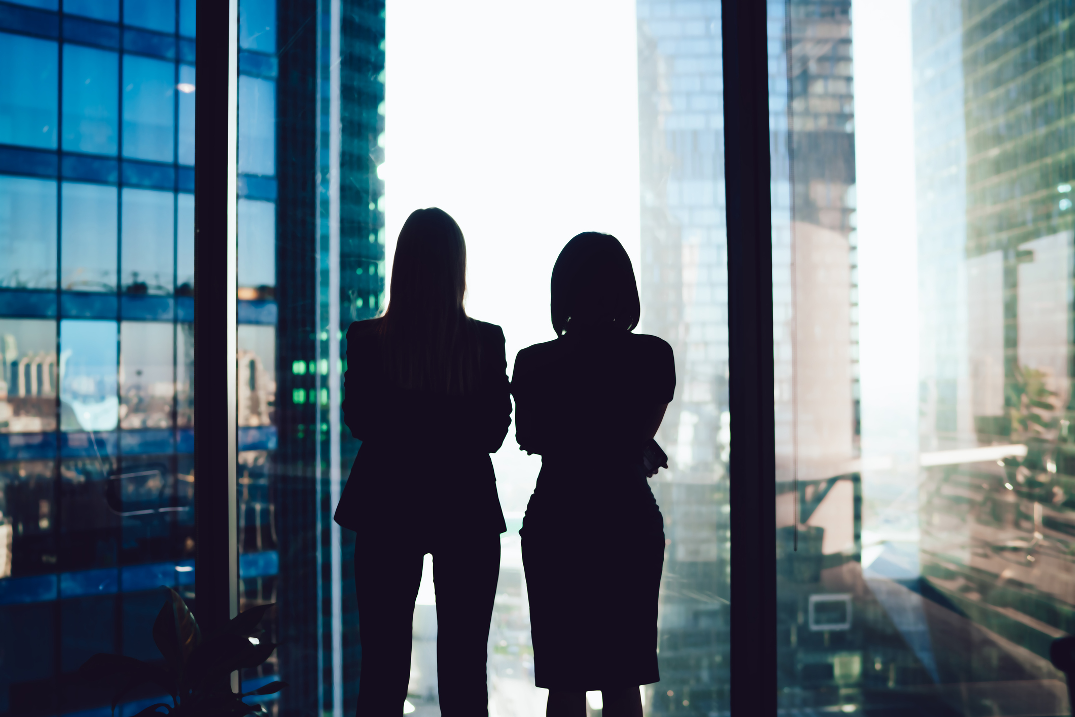 Two women looking out a window at high rise buildings