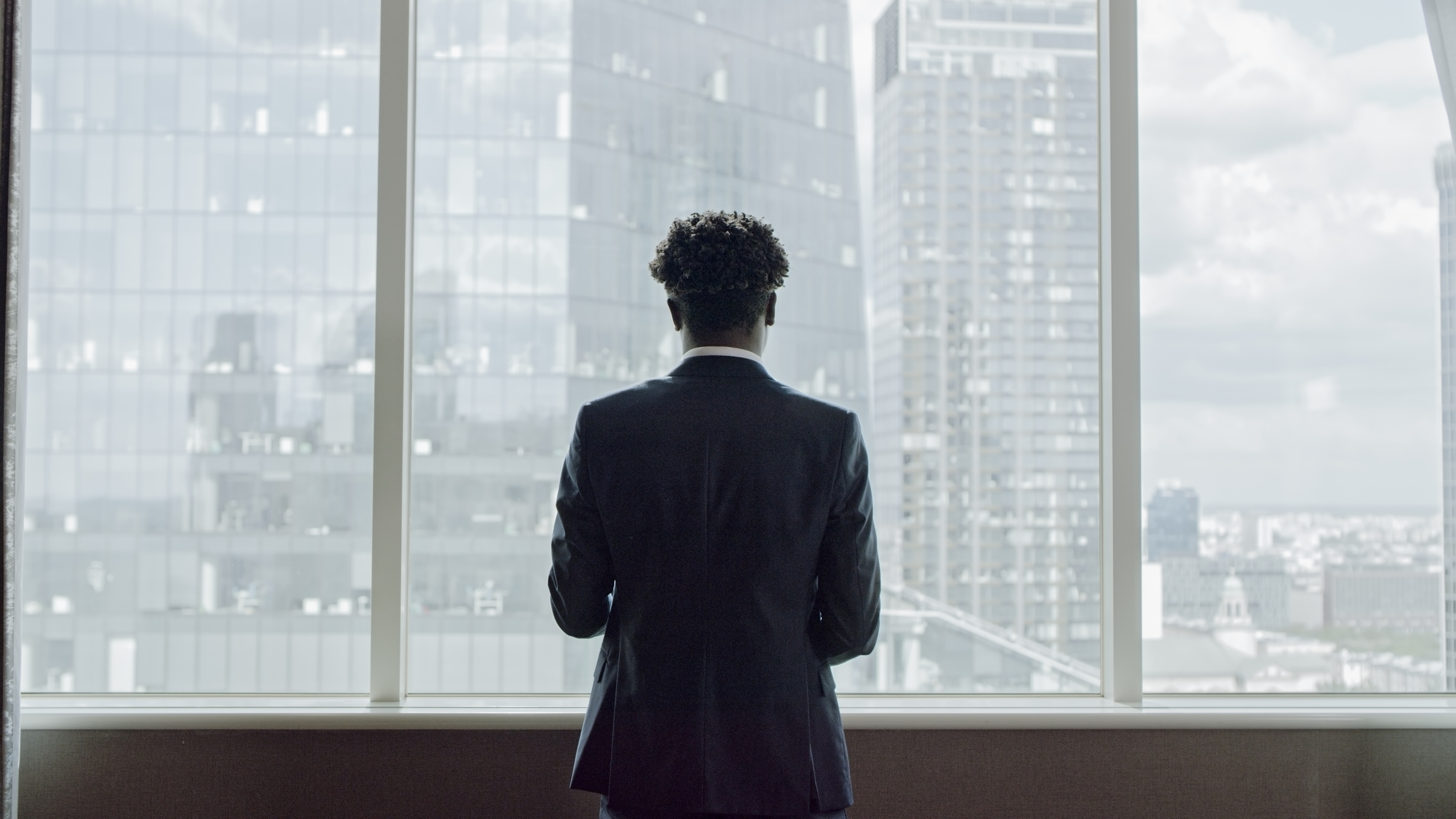 man standing looking out to buildings