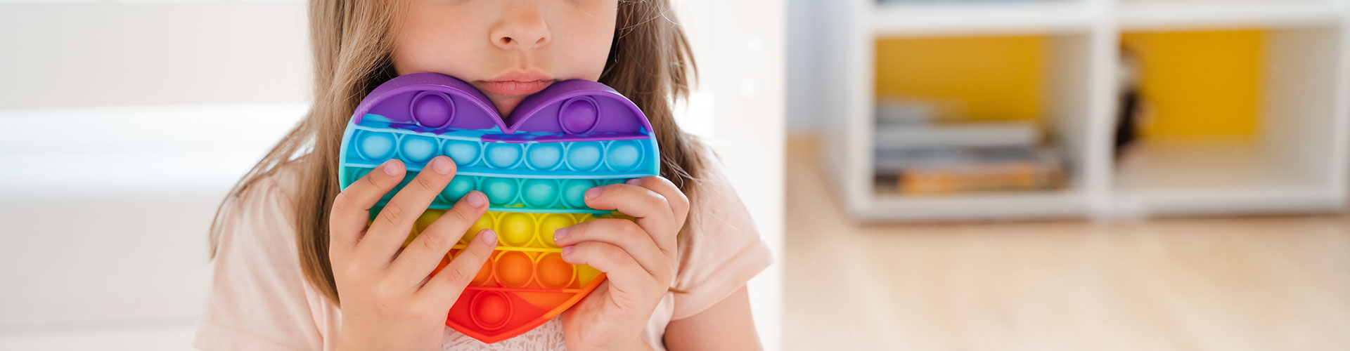 Child holding a rainbow coloured heart