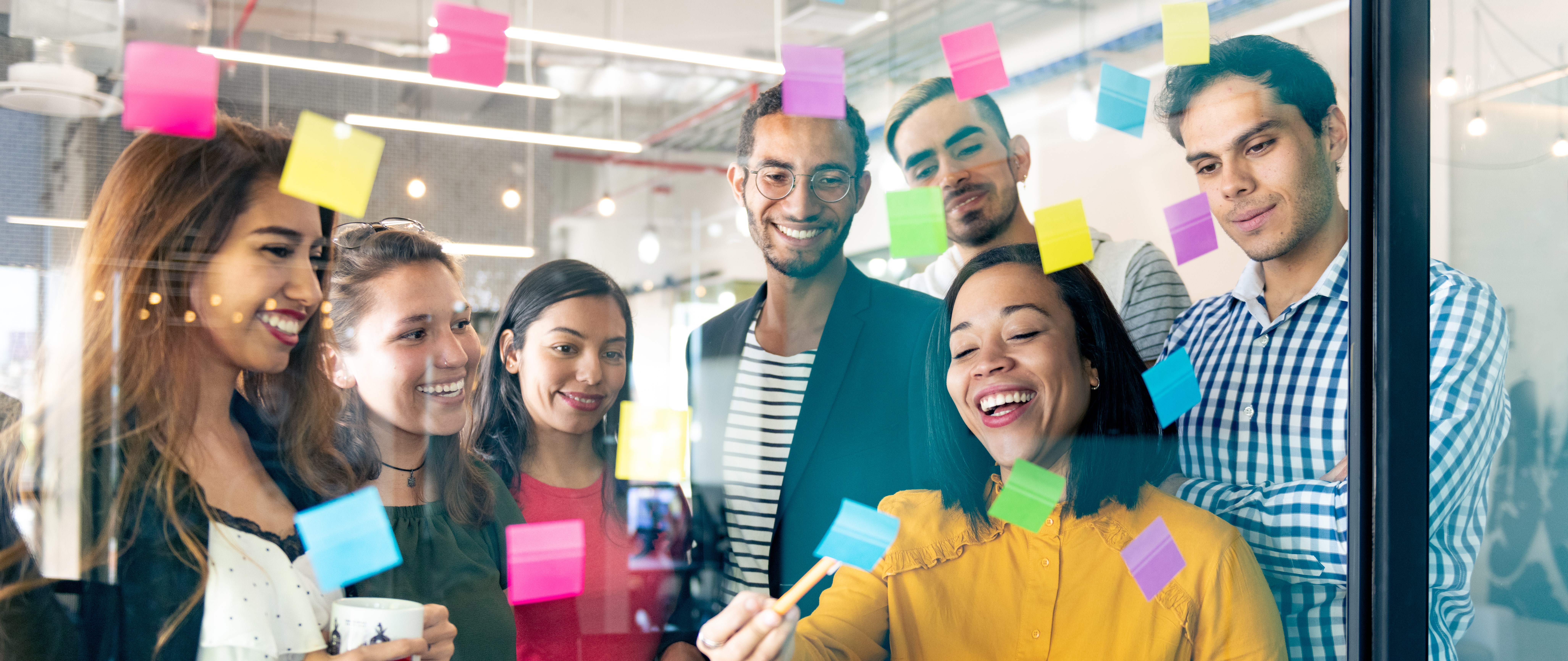 team gathered around window with sticky notes