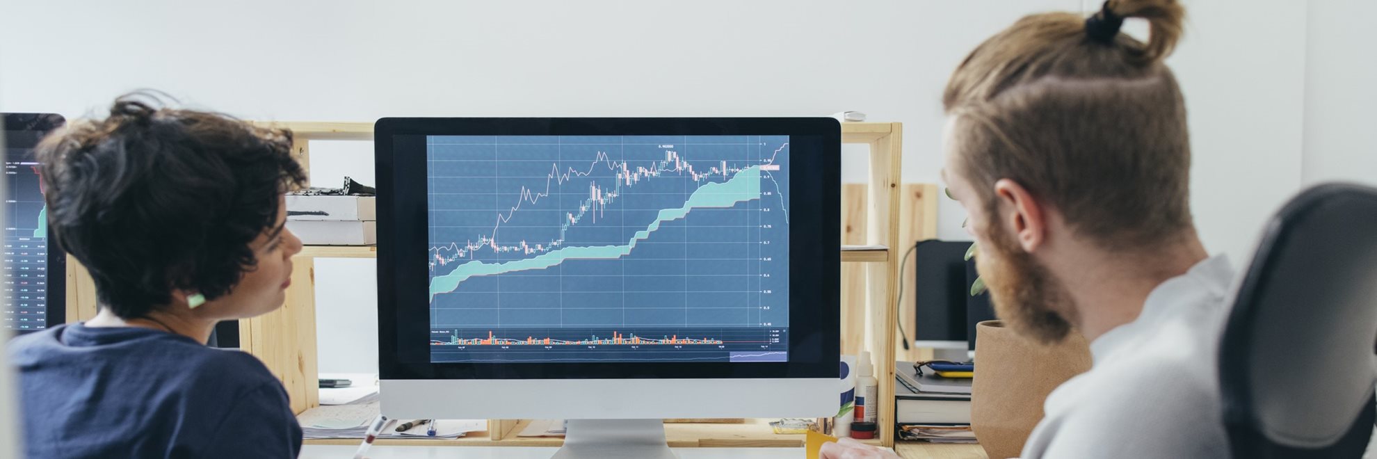 Two people looking at graphs on a computer screen